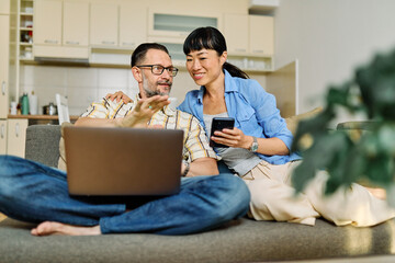 Portrait of a lovely young couple using a laptop and a mobile phone  together and having fun...