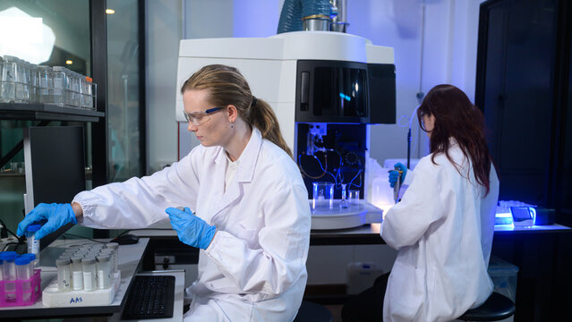 Female Scientists Working in Modern Research Laboratory with Advanced Analytical Equipment and Blue Lighting
