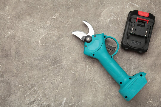 Blue garden battery powered pruning shears, secateurs, pruner on grey background. Gardening electric tool equipment.