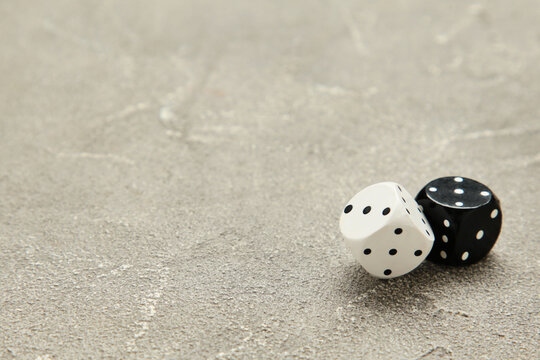 Two black and white dice on grey concrete background. Game cube
