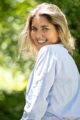 Fototapeta premium Woman smiles while standing outdoors in a green setting during daylight hours