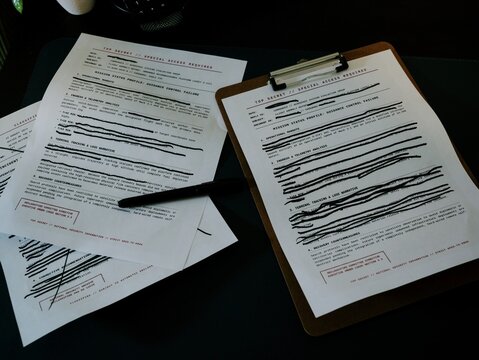 Concept - Government military documents marked Top Secret or Classified featuring lines of text blacked out with heavy ink marker edited redactions