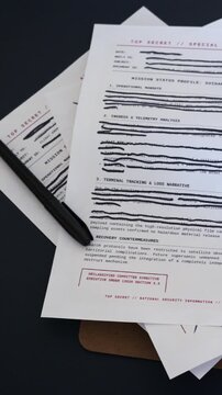 Concept - Government military documents marked Top Secret or Classified featuring lines of text blacked out with heavy ink marker edited redactions