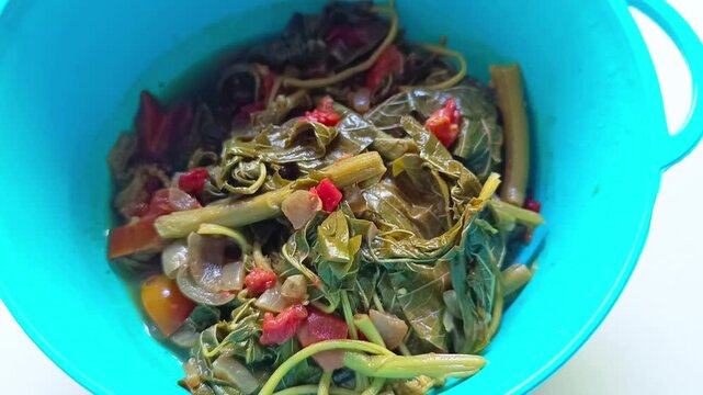 Traditional cooked chard stew with tomato and onion in blue bowl