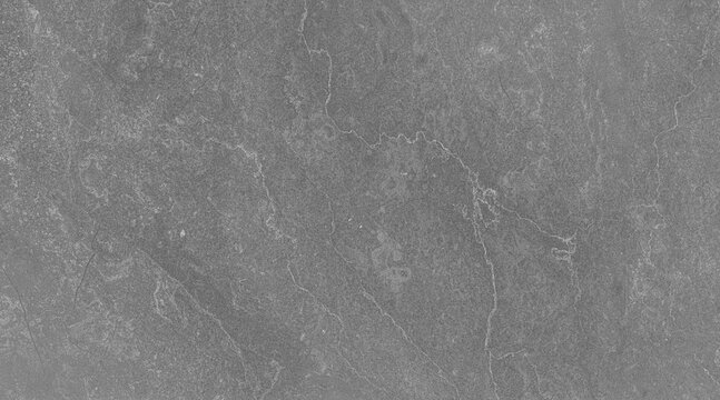 Close-up view of a grey textured stone surface, possibly slate or granite, with subtle linear patterns and natural imperfections. The muted tone and granular detail suggest a raw, earthy material.