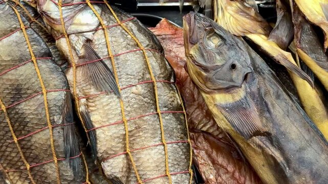 Cold smoked bream and walleye closeup, golden netting and textured scales on retail shelves, deli vendor arranging preserved fish