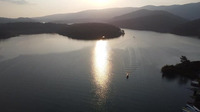 Drone aerial view of a boat cruising on Tuyen Lam lake at sunset in Da Lat Vietnam