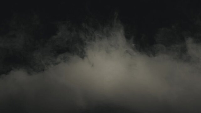 Static low angle shot of dense theatrical smoke and fog billowing heavily across a dark stage floor. Soft semi-warm white lighting creates a textured