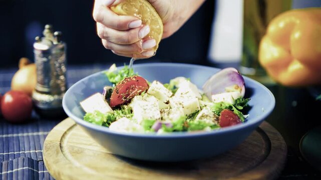 Cook Squeezing Lemon Juice over Fresh Vegetable Salad with Feta Cheese. Greek Salad 