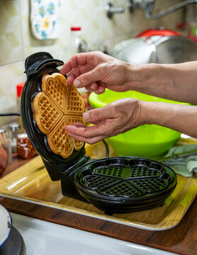 The hostess prepares the cakes heart waffle,old-fashioned way, using traditional European cuisine and utensils.