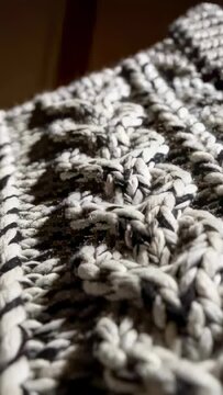 Vertical video: Pulling back camera revealing braided cable knit panel at home showing yarn texture