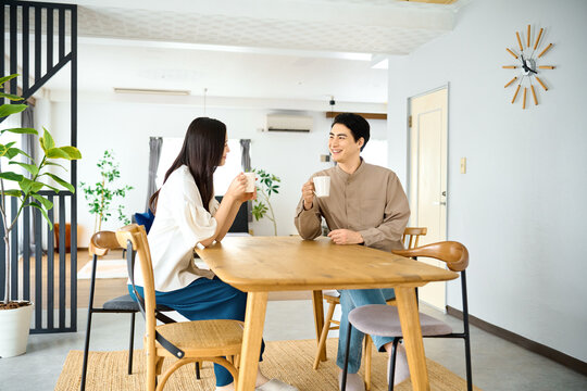 ダイニングテーブルでコーヒーを飲み談笑する夫婦