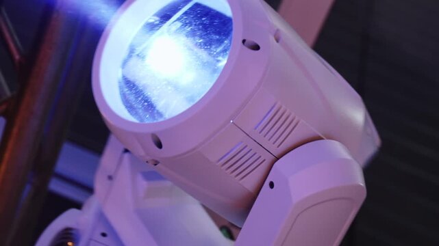 Rotation of stage controlled lighting fixture during party closeup. Dynamic shot with color change at disco during dancing. Club stage lighting for atmosphere and mood.