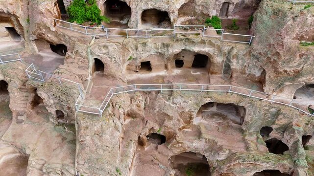 Aerial close-up shot of Vardzia cave monastery rooms and tunnels. Detailed drone view of the ancient rock-hewn windows and chambers carved into the steep cliffside in Georgia