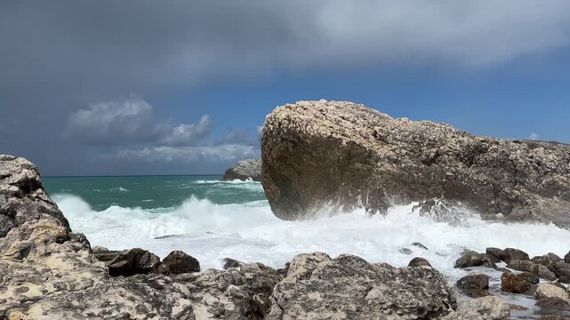 Turquoise Atlantic water after a storm with powerful surf and white sea foam rolling across the rocky coastline under changing weather
