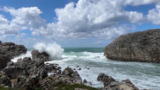 Atlantic surf moving through sunlit limestone cliffs beneath a vast sky with towering clouds after a storm