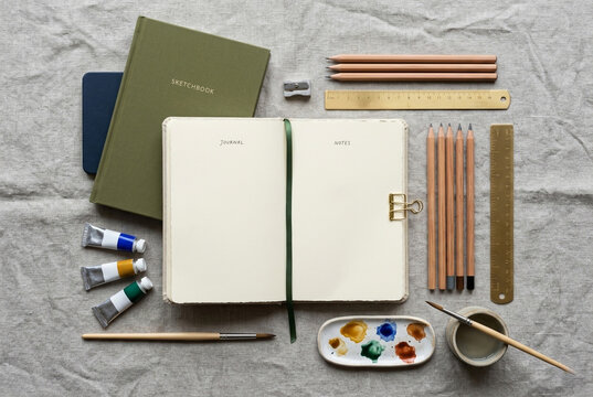 Flat lay of artist materials with sketchbook pencils and watercolor paint
