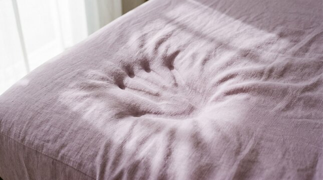 Minimalist background photograph showing a gentle hand imprint on a soft pastel lavender linen memory foam texture with shadows