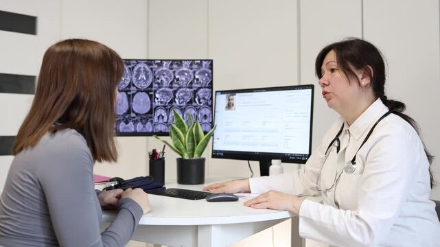 Young woman receives emotional support from doctor during difficult medical consultation while discussing brain scan results and future treatment decisions in private clinic
