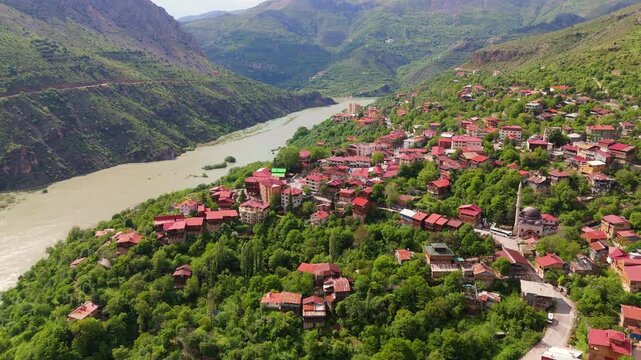 Aerial panoramic view of Kemaliye town in Erzincan, Turkey. Scenic drone shot of traditional houses with red roofs terraced on steep mountain slopes above the winding Karasu River