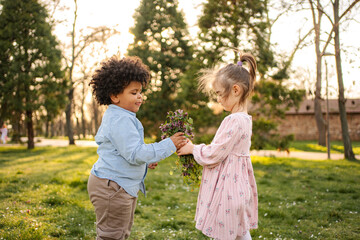 Obraz premium Children sharing flowers in park expressing friendship