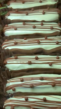 Close-up mint eclairs lined in rows smooth pale green icing with chocolate drizzle and bead toppings neat paper liners modern cafe