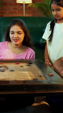 Family playing carrom board game together at home, enjoying bonding time with young children