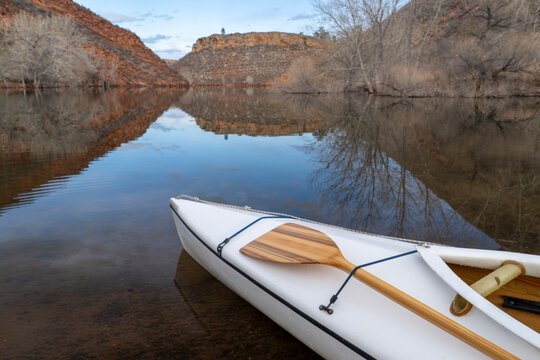 decked expedition canoe with a wooden paddle on a shore of Horsetooth Reservoir in northern Colorado in cold season scenery