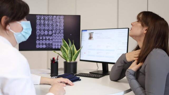 Sick young woman coughing during medical consultation patient showing flu or respiratory illness symptoms while visiting doctor in modern clinic office