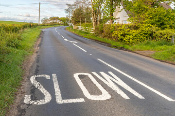 Naklejka premium Slow Road Marking on Rural Country Lane Before Dangerous Bend