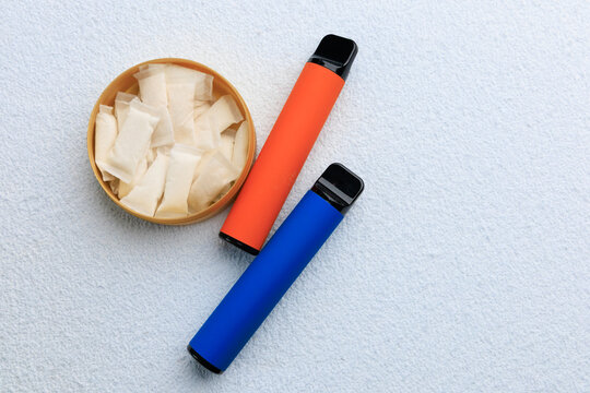 Snus pouches and electronic cigarettes placed on a light surface in a casual setting