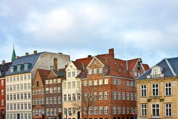 Fototapeta premium COPENHAGEN - Scenic row of traditional European buildings in central Copenhagen, Denmark, featuring classic architecture, red rooftops, and charming facades