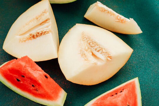 Freshly cut fruit on a green cutting board with slices of watermelon and melon arranged in a simple pattern