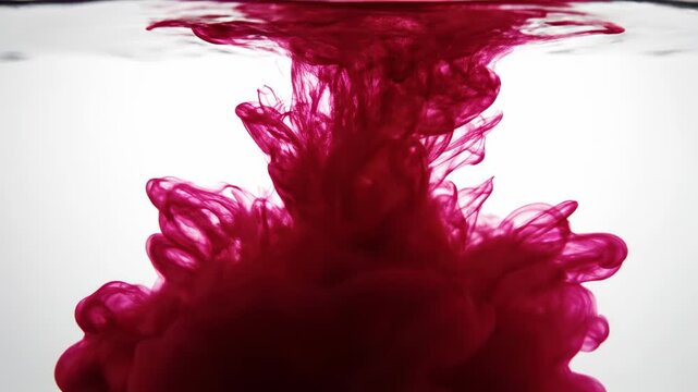 Vibrant crimson pigment disperses dramatically within clear liquid, creating ethereal, organic cloud formations that swirl and evolve into intricate, artistic patterns conveying dynamic motion