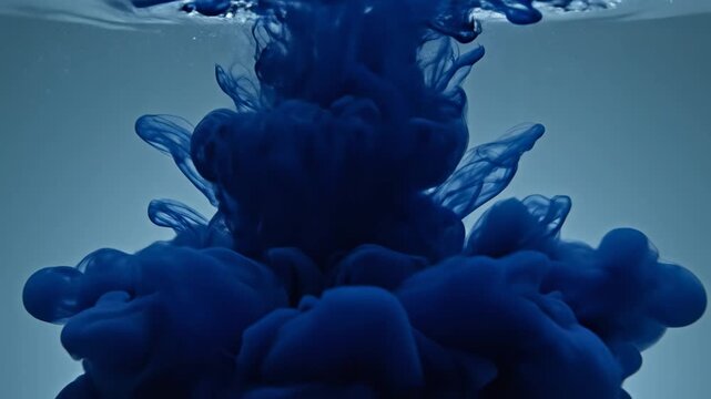 A vibrant, deep blue liquid pigment gracefully disperses and swirls within clear water, creating an abstract, organic explosion of ethereal, fluid shapes and captivating undulations resembling