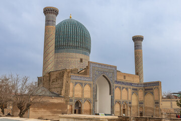 Obraz premium External view of the Gur-e-Amir Mausoleum showing the iconic blue dome, flanking minarets, and intricate mosaic tilework on the facade.