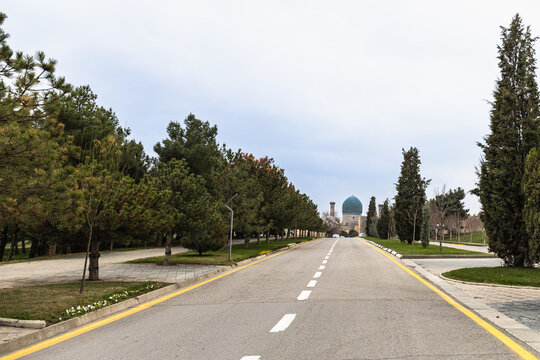 Wide-angle view of a modern asphalt road in Samarkand leading toward the blue domes of the Amir Temur Mausoleum