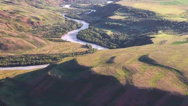 Panoramic drone view of Naryn River valley with wide meanders and grassy hillsides, Kyrgyzstan