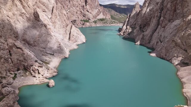 Wide aerial panorama of Kol-Suu Lake basin surrounded by cliff walls and Tian Shan mountains, Kyrgyzstan