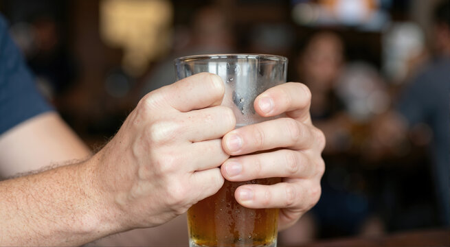 Tense sports fan gripping a glass of beer. Macro shot of white knuckles showing match stress