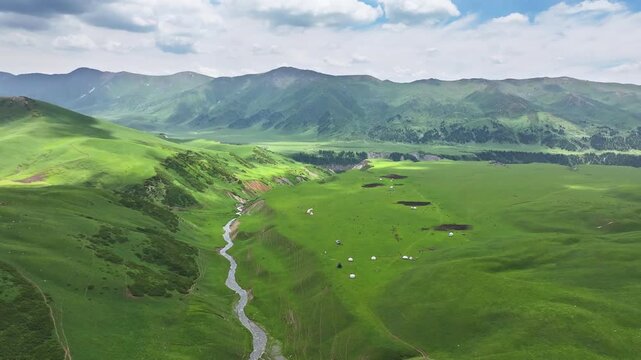 Drone flying over green summer pastures with nomadic yurt camps in At-Bashi Valley, Kyrgyzstan