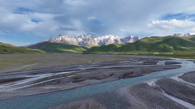 Low drone flight over braided river floodplain in Kok-Kiya Valley with Kakshaal Too peaks, Kyrgyzstan