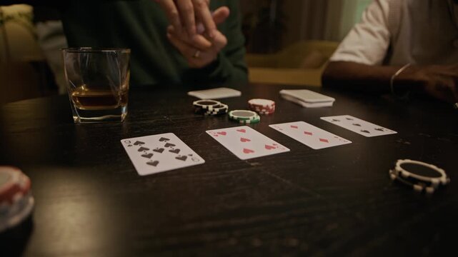 Close up of anonymous man dealing playing card on dark wooden table while preparing for poker with friends