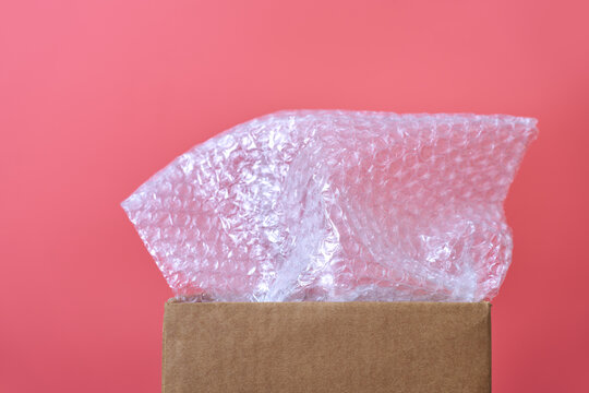 Bubble wrap sticking out of open cardboard box on pink