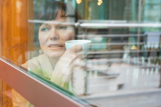 Professional business woman with coffee in city cafe window