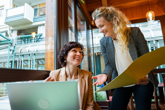 Business women discussing project in cafe with laptop