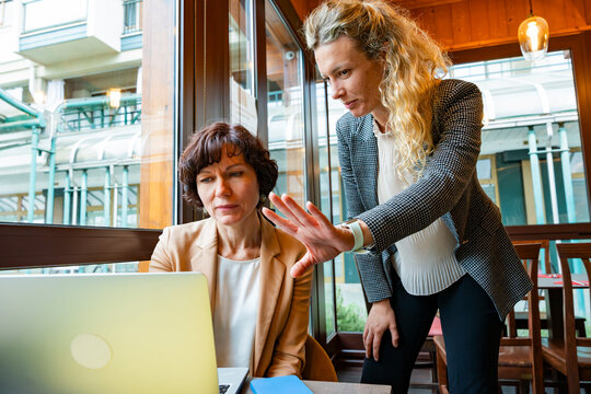 Businesswomen collaborating on laptop in modern cafe