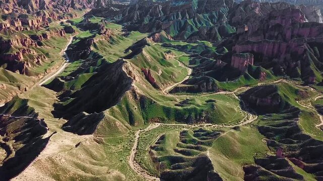 Drone sweeping across eroded Danxia pillars and canyons at Binggou Geopark, Zhangye, China