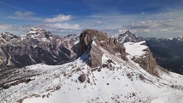 Drone flying over snow plateau with dramatic Dolomite spires in background, Cortina, Italy