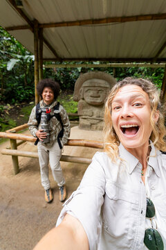 Travelers taking selfie by San Agustin stone statue